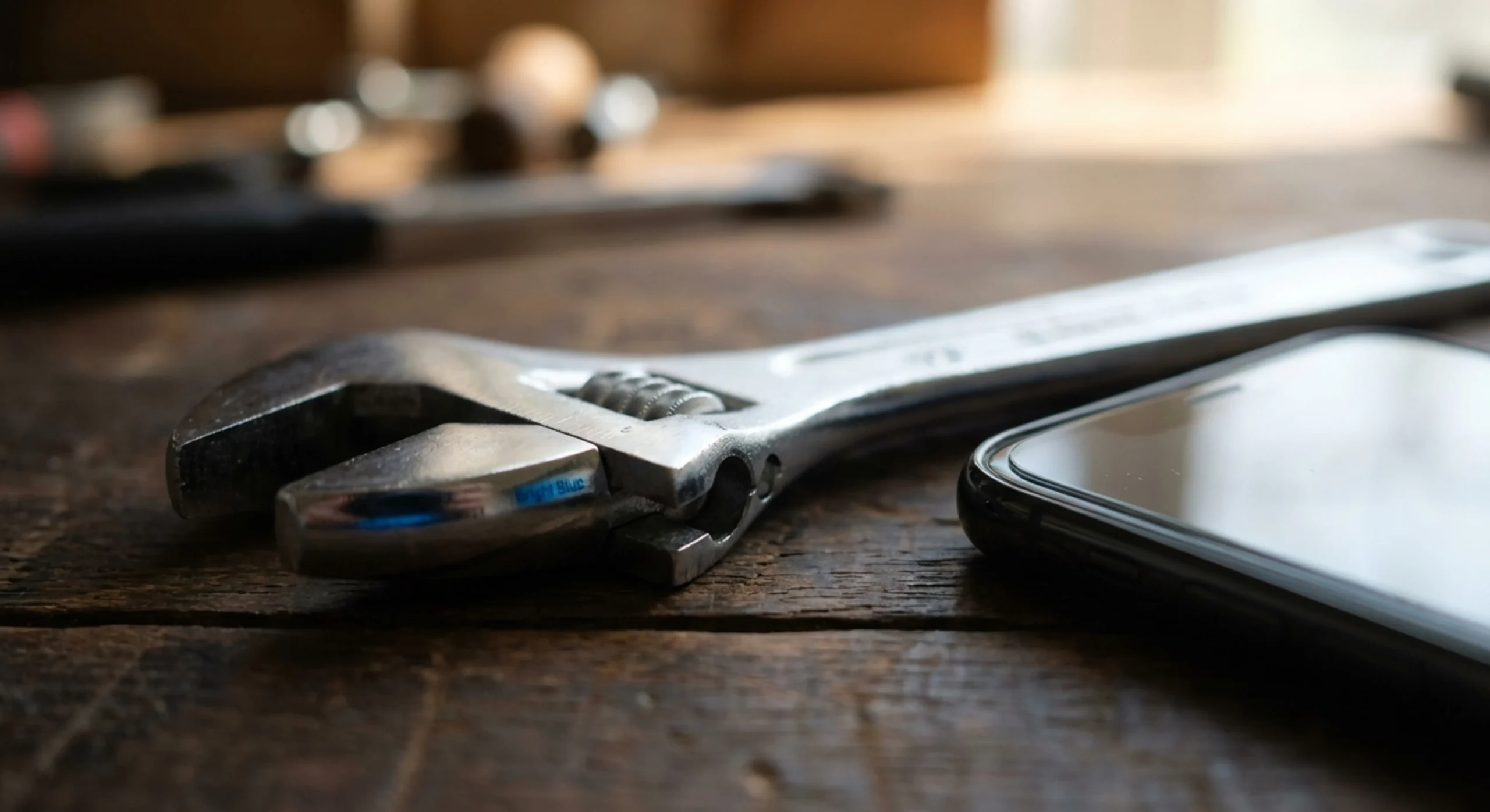 Gros plan artistique d'une clé à molette professionnelle et d'un smartphone, symbolisant le lien entre le métier et la gestion des appels.